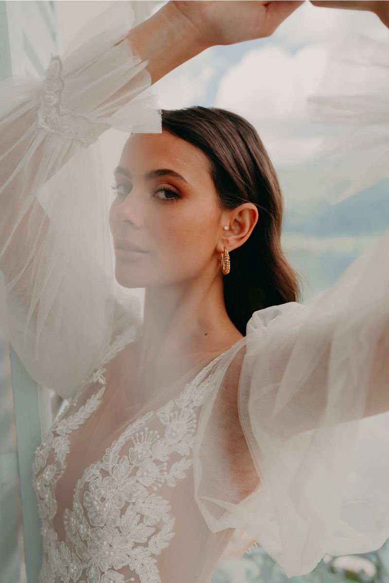 Mariée en robe de dentelle aux manches voile, maquillage naturel lumineux