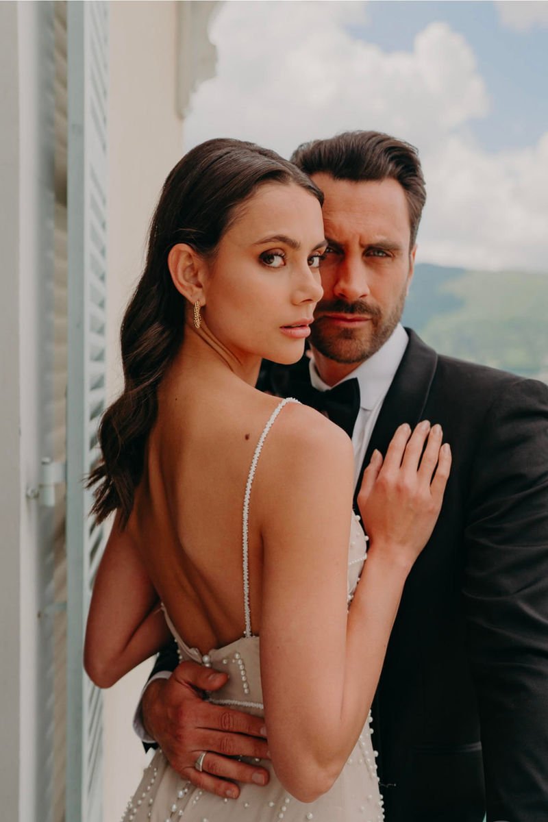 Couple de mariés à la fenêtre, coiffure de mariée attachée
