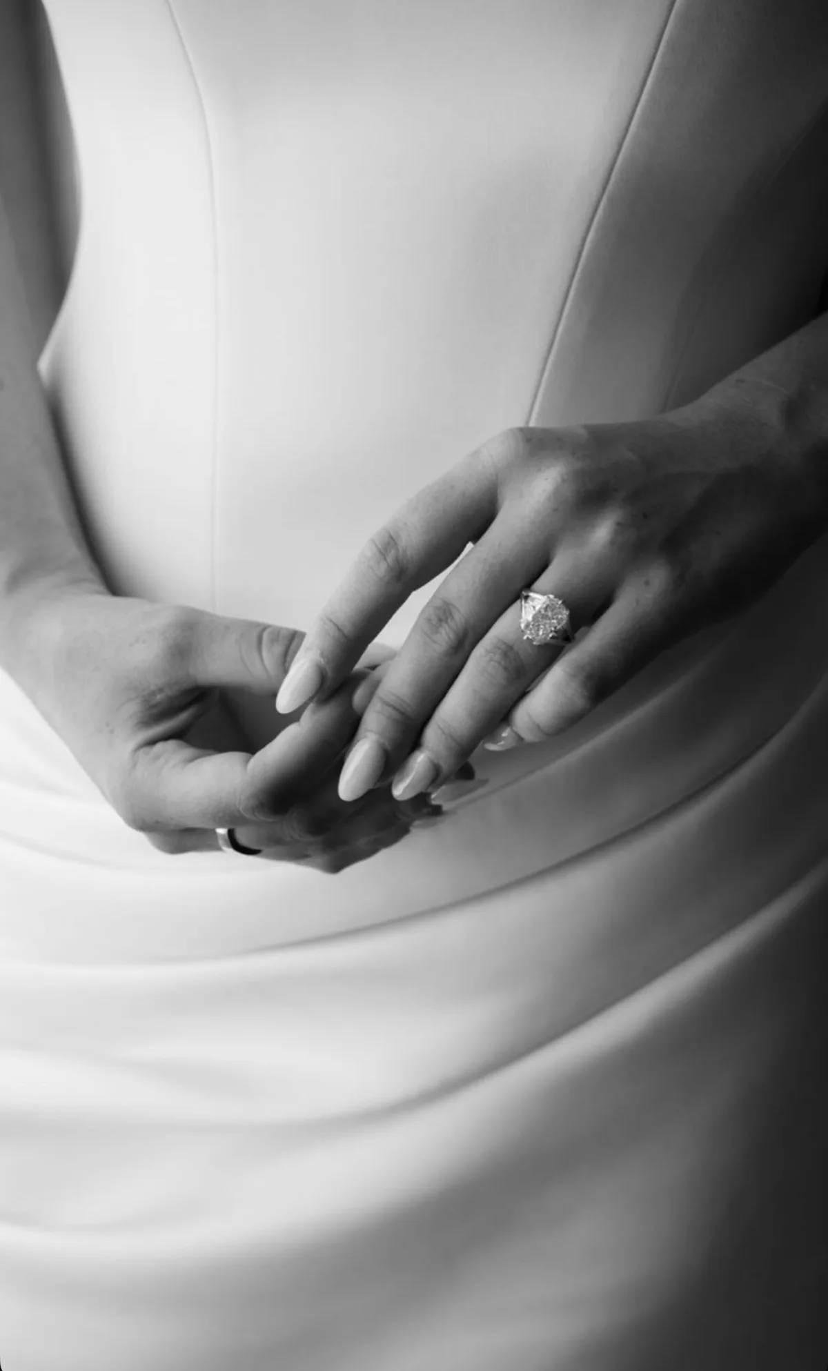 Mains de la mariée et bague de fiançailles sur la robe
