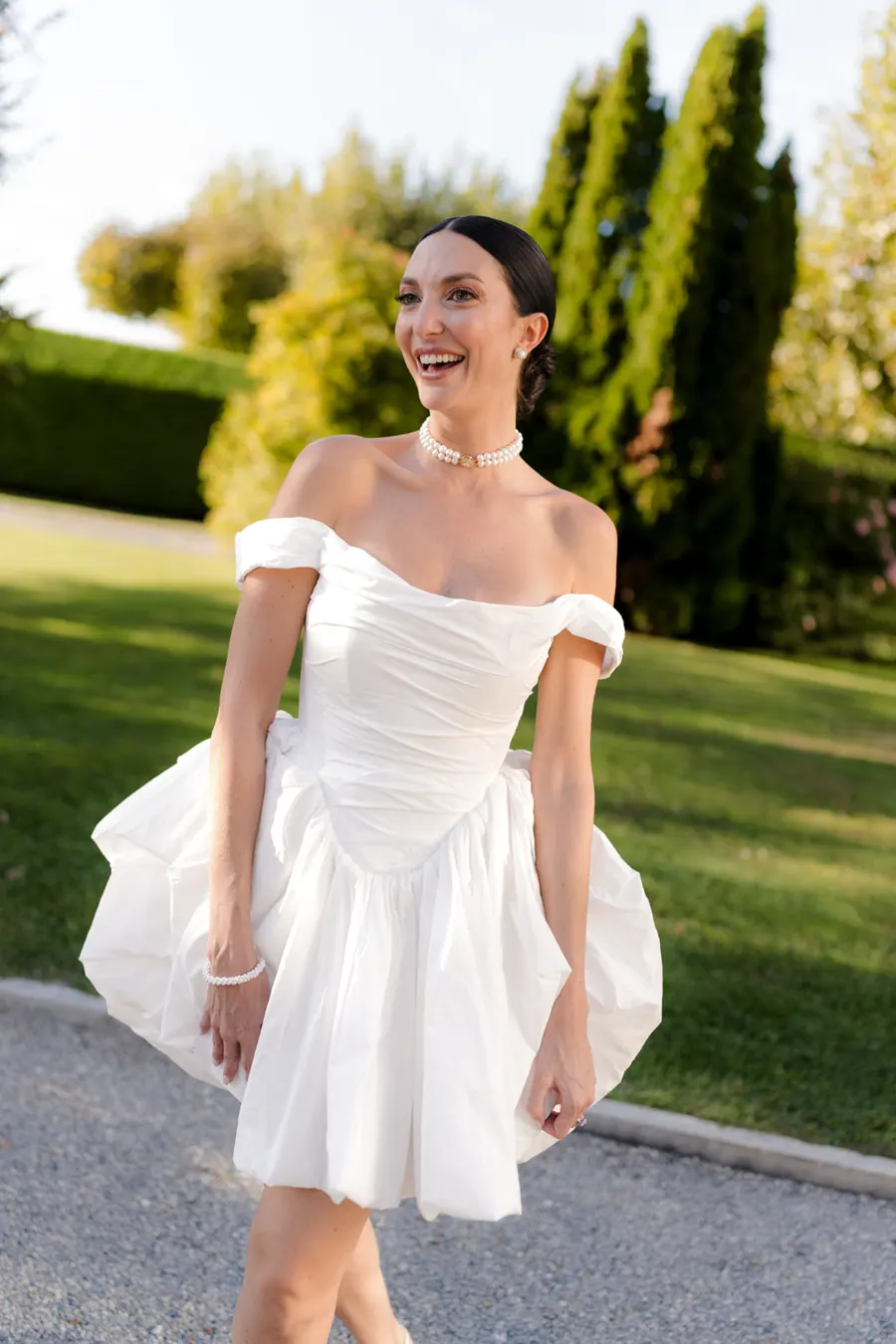 Mariée en robe courte qui rit dans les jardins