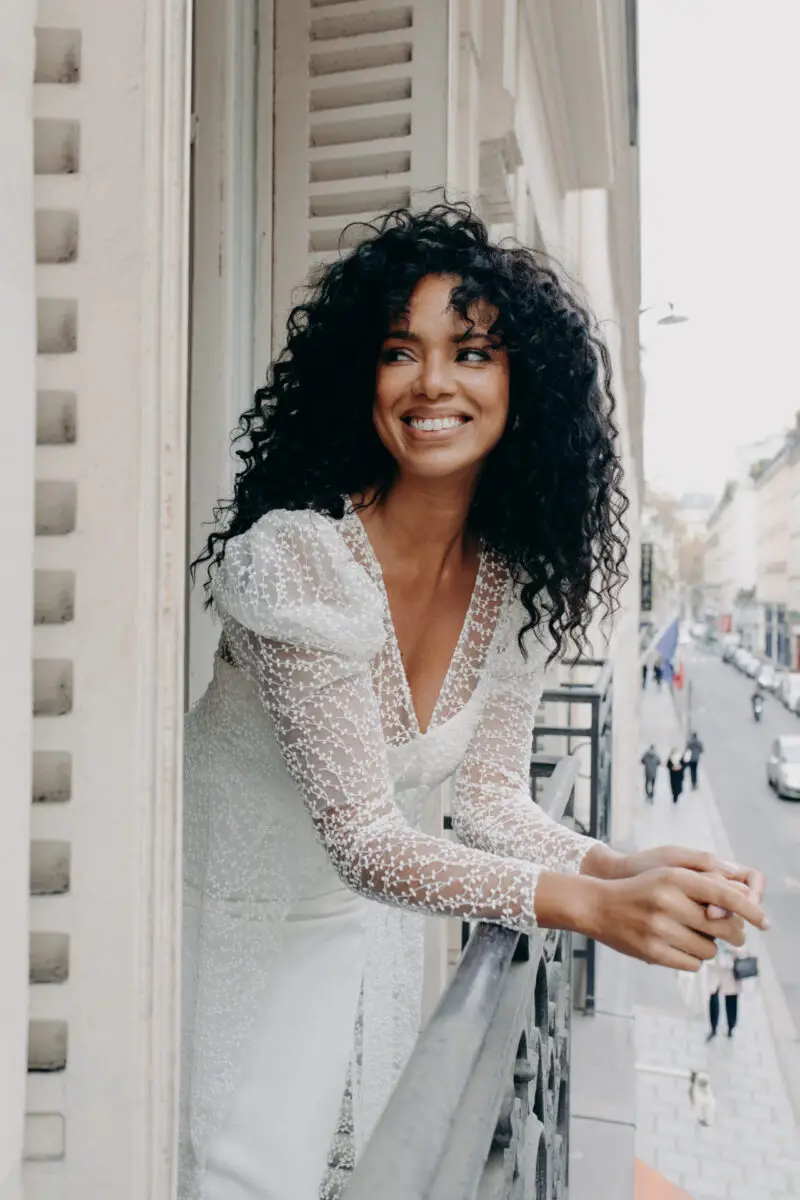 Mariée aux cheveux bouclés au balcon, maquillage lumineux