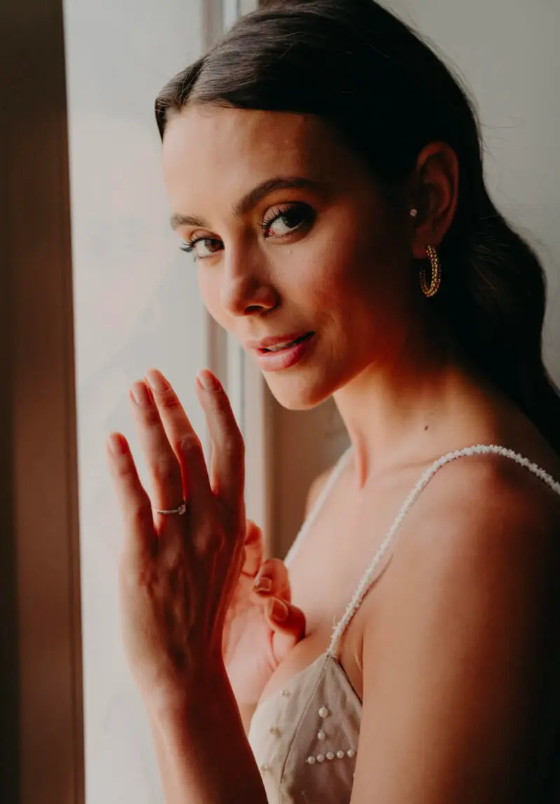 Portrait de mariée à la fenêtre, maquillage naturel et coiffure lissée